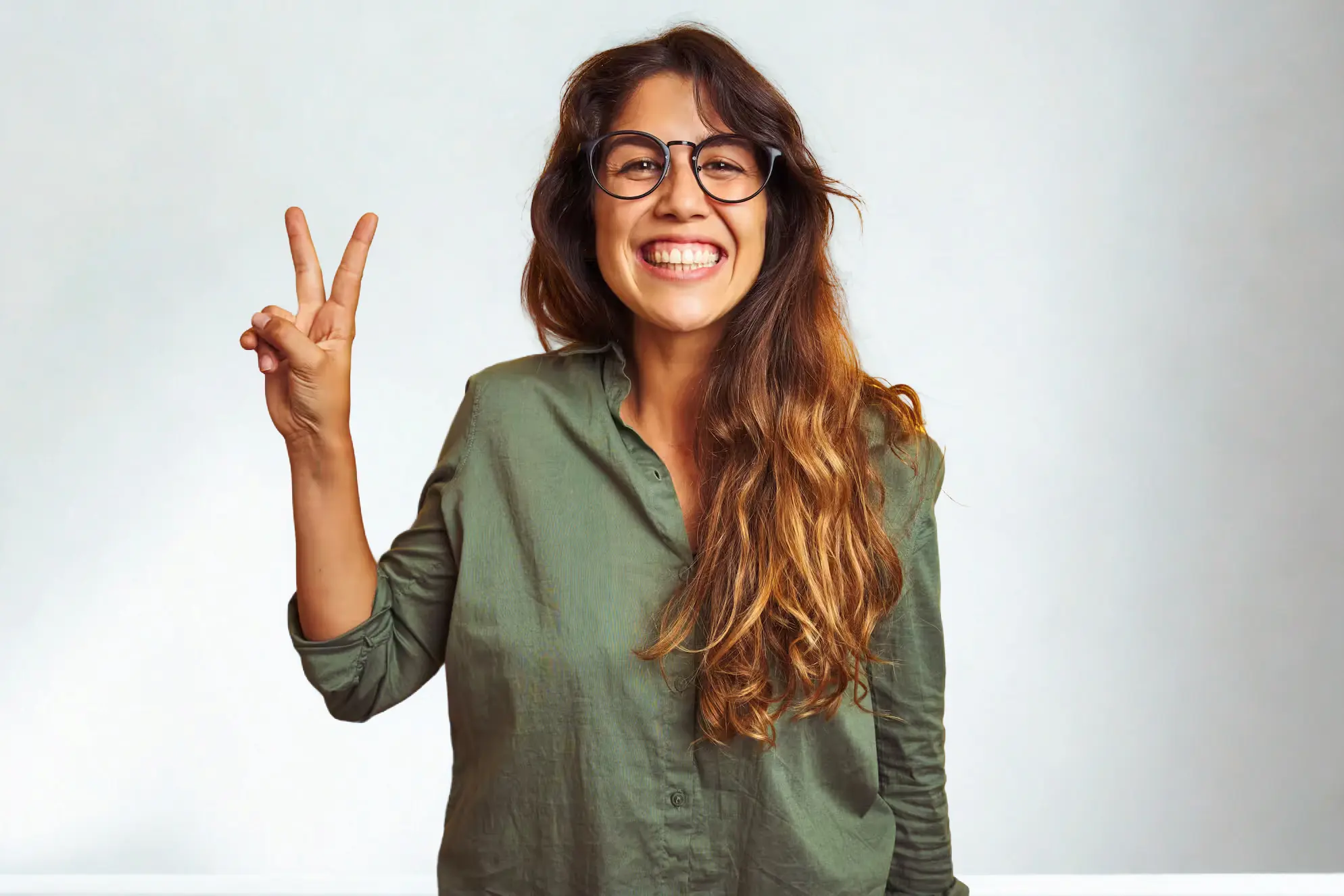 Young beautiful woman wearing green shirt and glasses over white isolated background showing and pointing up with fingers number two for the top benefits of oursourcing while smiling confident and happy.