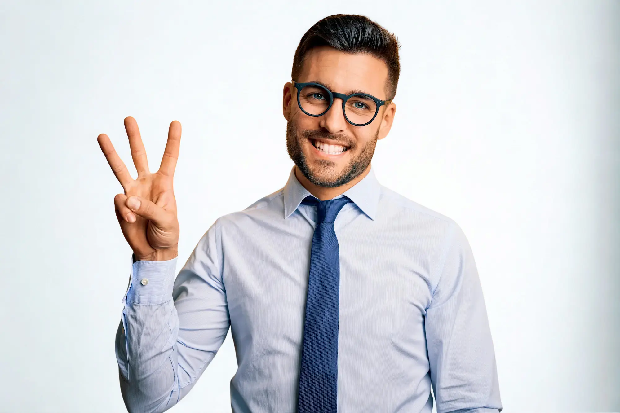 Young handsome businessman wearing tie and glasses standing over white background showing and pointing up with fingers number three for the top benefits of sourcing while smiling confident and happy.