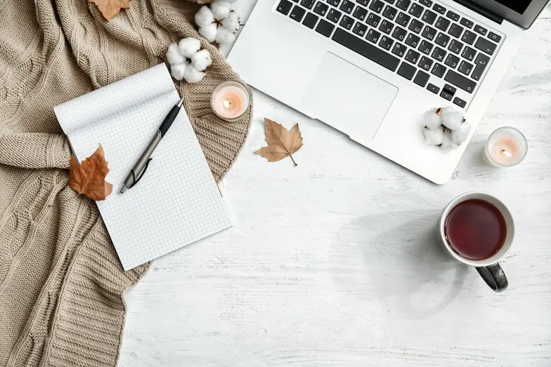 Laptop with candle and notebook for paperless bookkeeping habits and a calm year-end