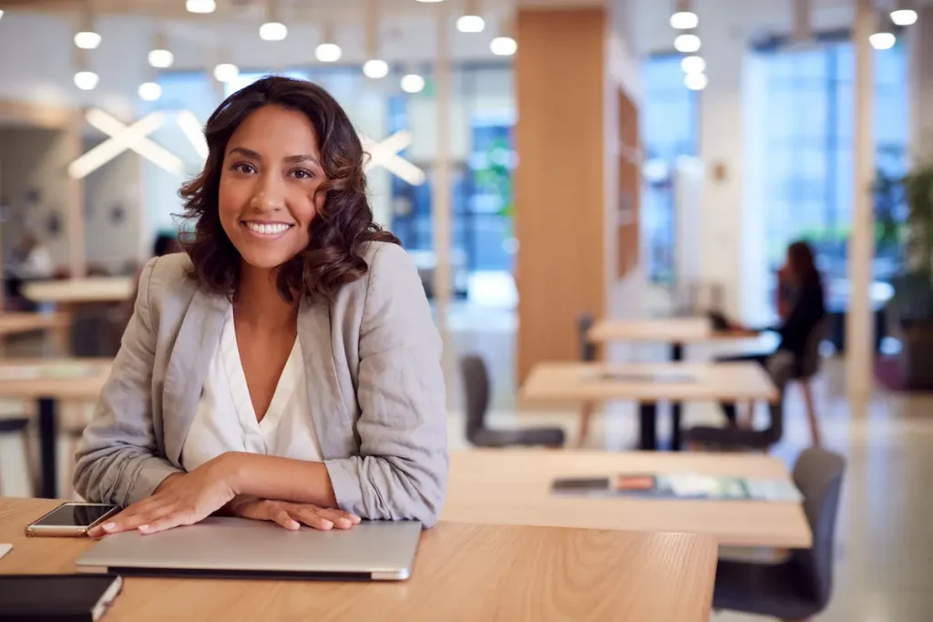 Woman sitting at a desk with a closed laptop, smiling calmly, symbolising peace of mind and confidence after completing tax planning.